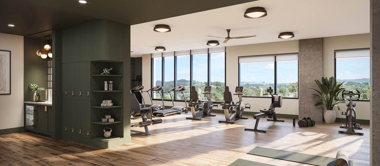 Well-equipped fitness center with cardio machines, a bright open space, wooden floors, and large windows offering scenic views of the outdoors.